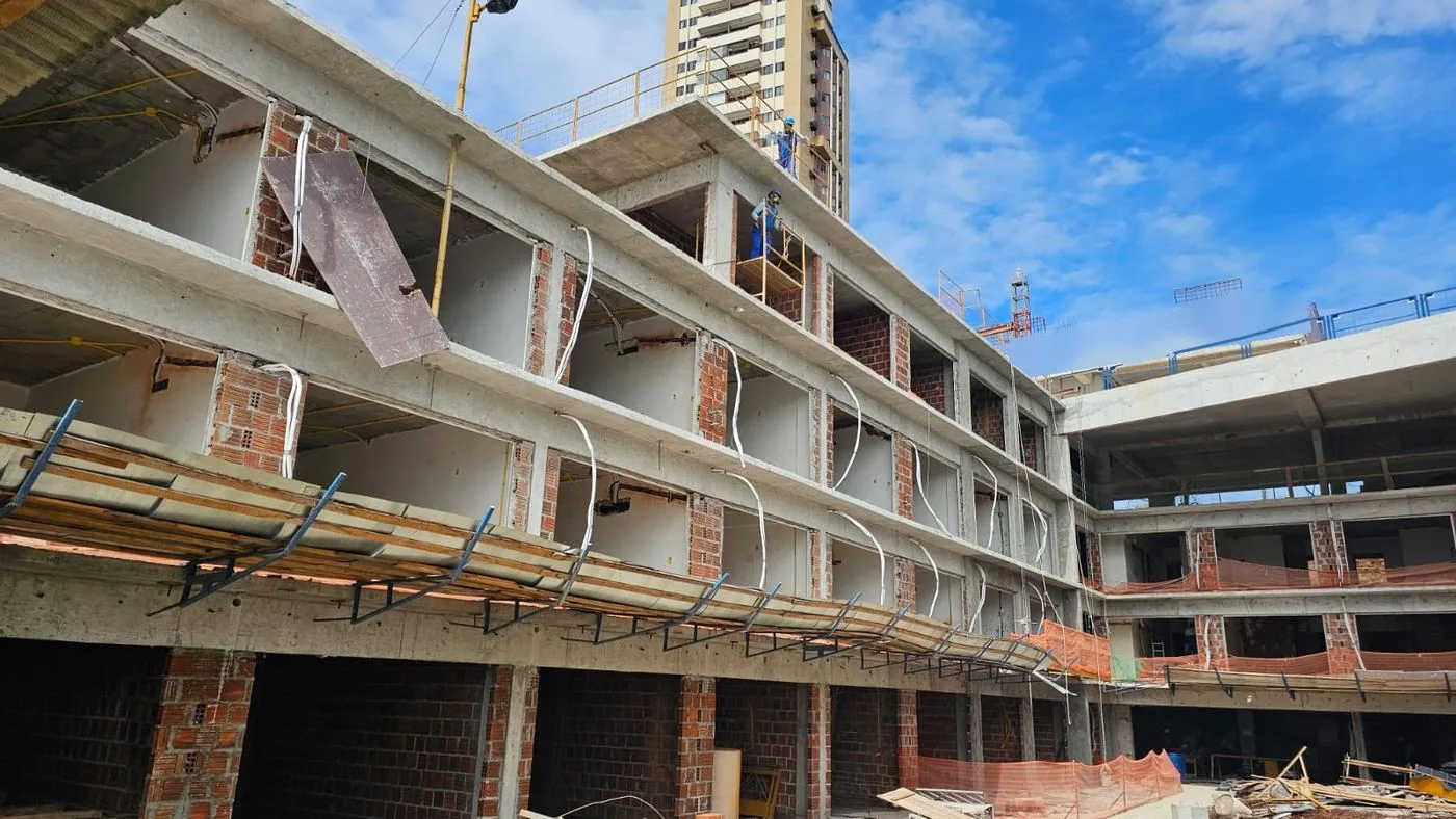 Estrutura da obra com a fachada em construção e o prédio vizinho ao fundo