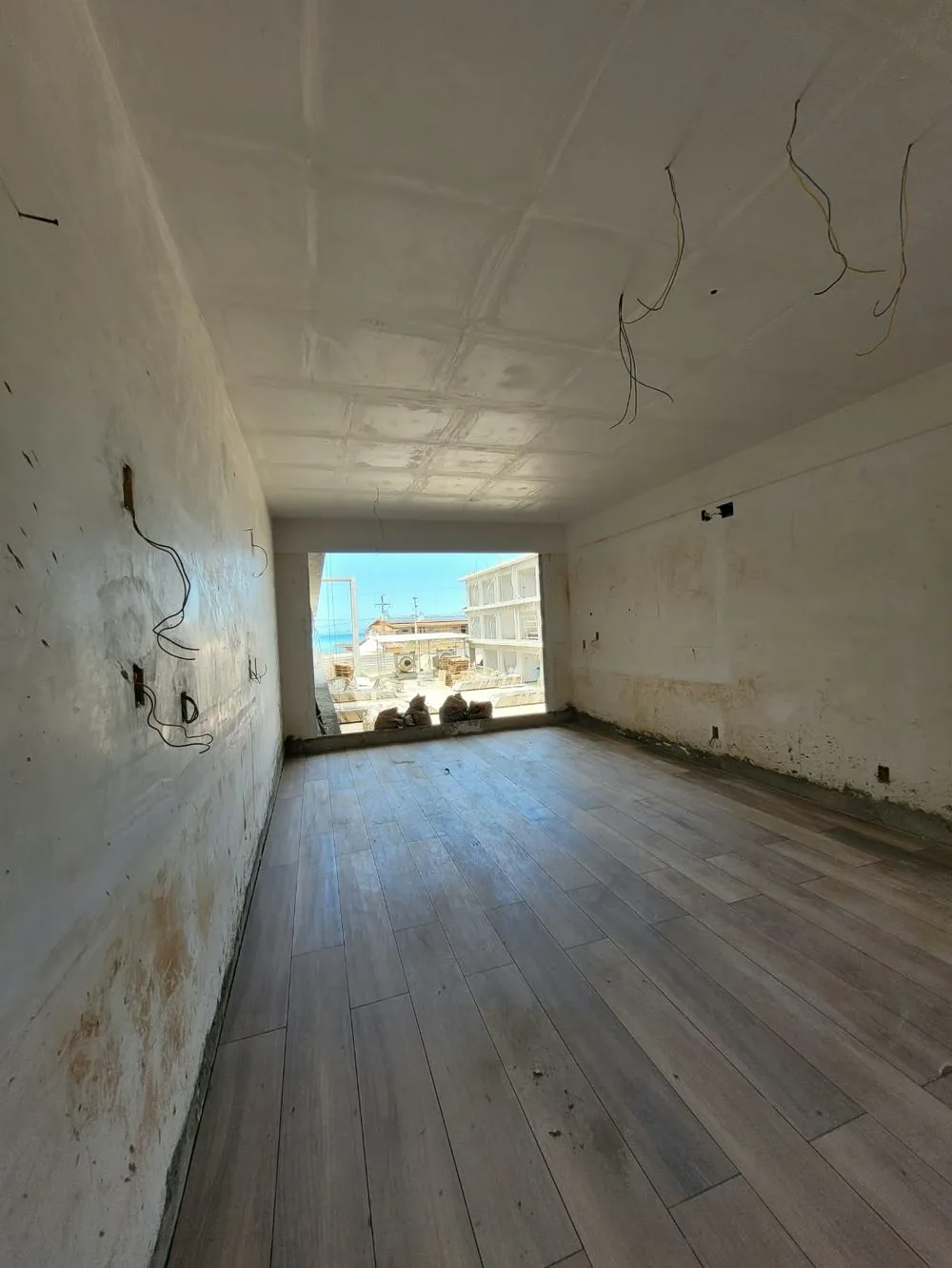Interior de uma unidade com piso instalado e janela com vista para o mar